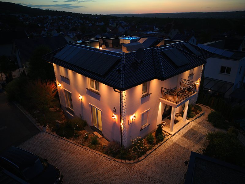 Das Haupthaus am Abend von oben, mit beleuchtetem Whirlpool auf dem Dach