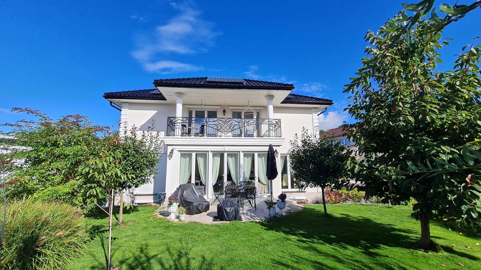 Die Villa Unter dem Schloss vom Garten aus, mit Rasen und Terrasse