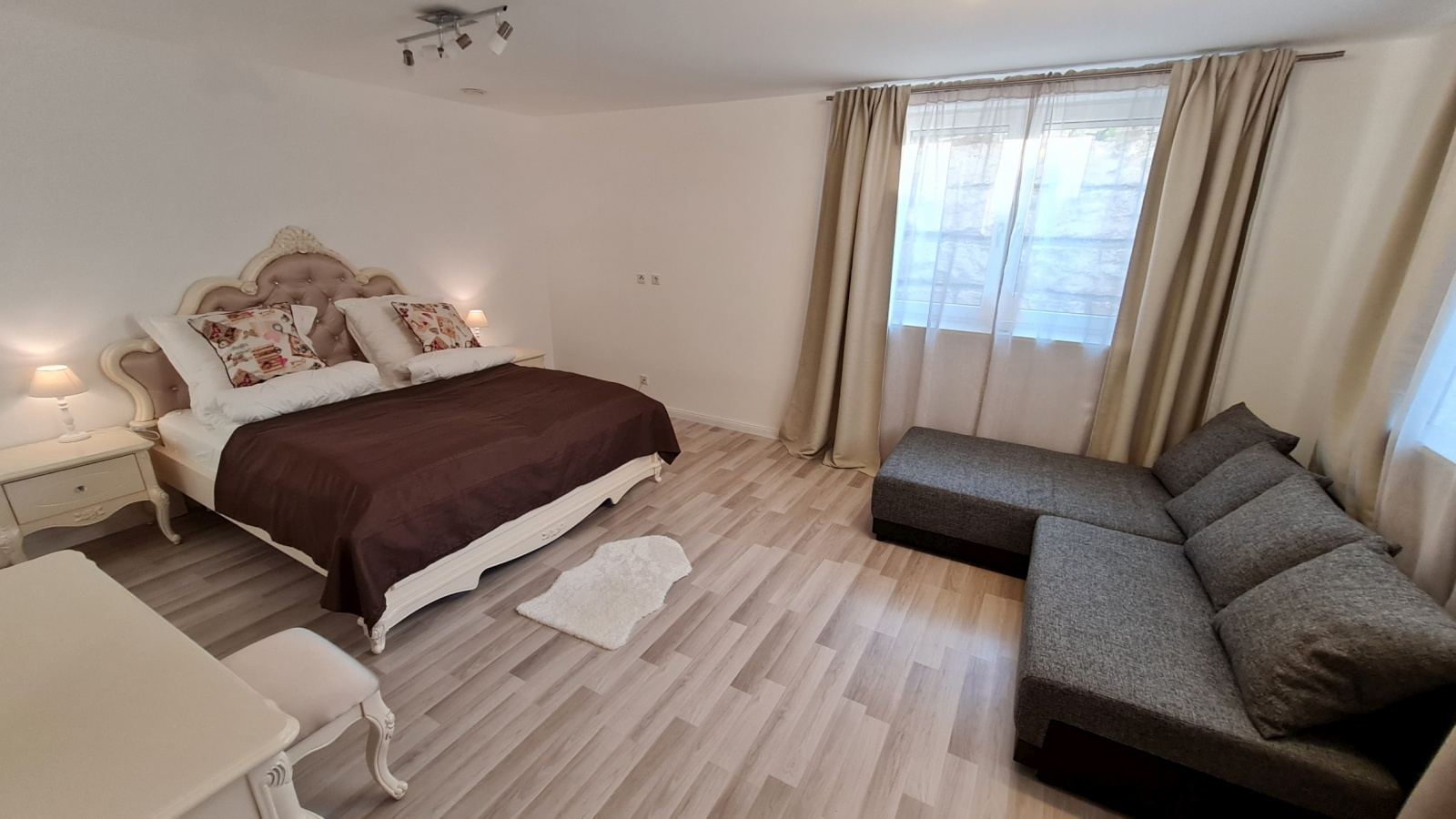 Schlafzimmer mit Kingsize-Bett und Eckcouch